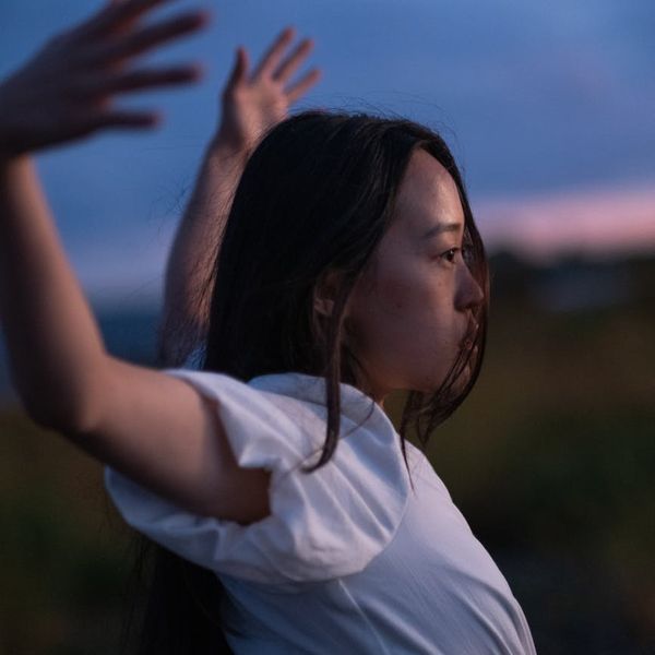 Person stretching gently outdoors with a serene natural background.